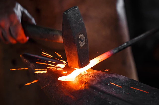 ハンマーで金属を叩いて強くしている鍛造製法の写真